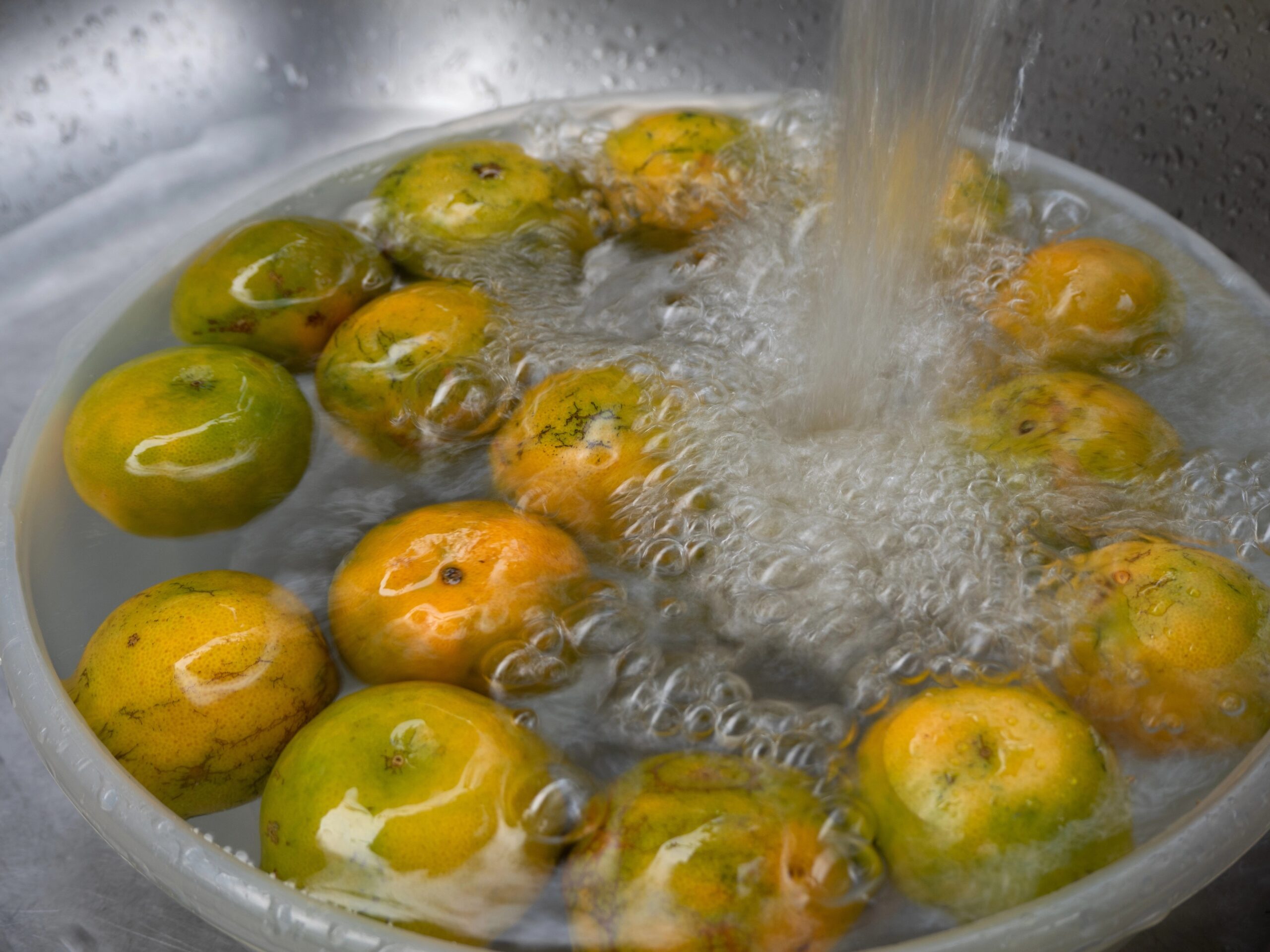 Mandarine namočene v vodi v posodi med pranjem.