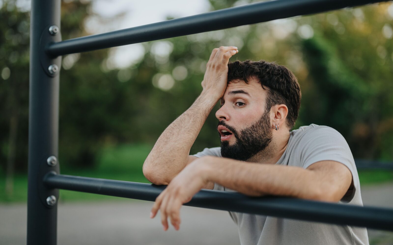 Utrujen moški se po vadbi naslanja na vadbeno lestev - upad telesne kondicije in mišične moči po 35. letu