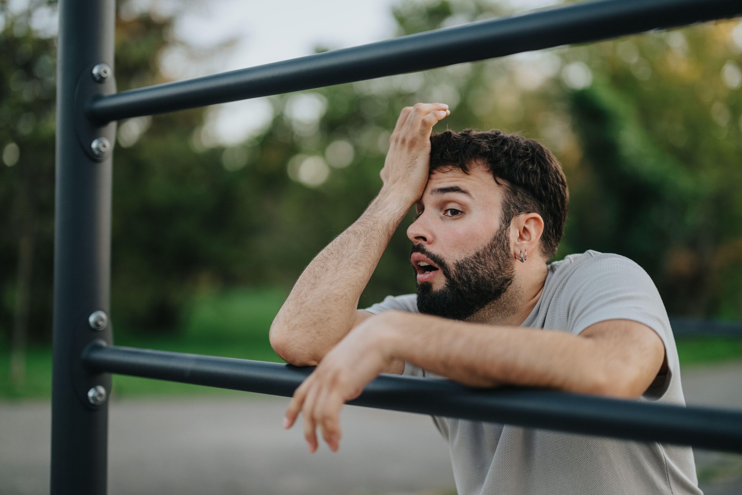 Utrujen moški se po vadbi naslanja na vadbeno lestev - upad telesne kondicije in mišične moči po 35. letu