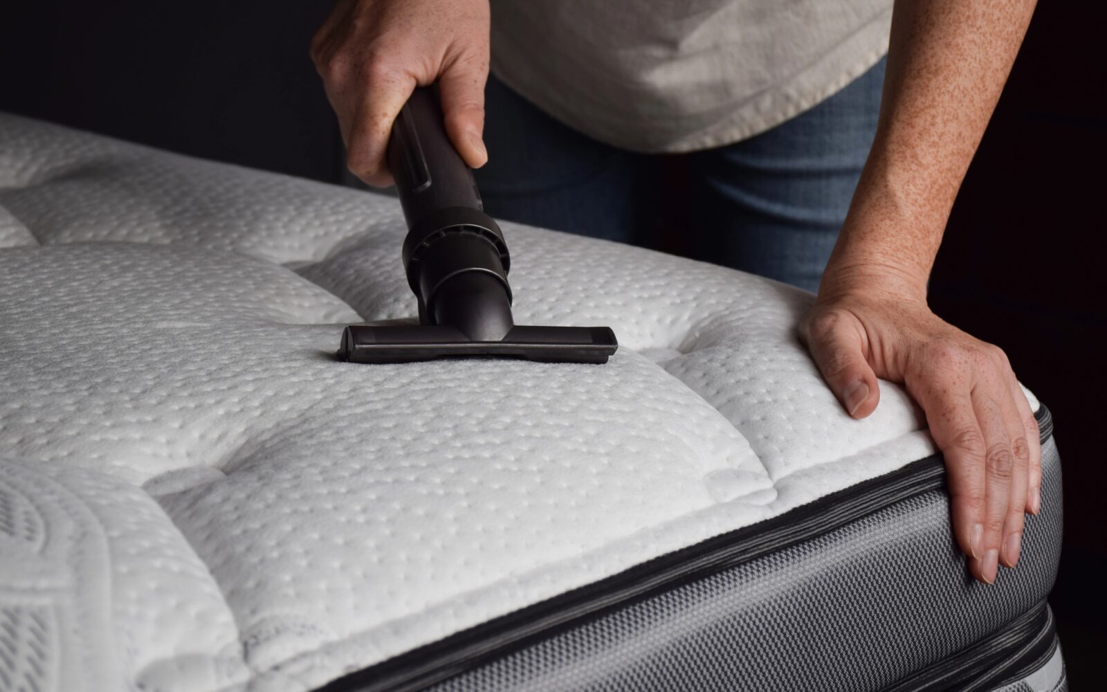 Ženska uporablja globinski sesalec, da globinsko očisti vzmetnico polno pršic.