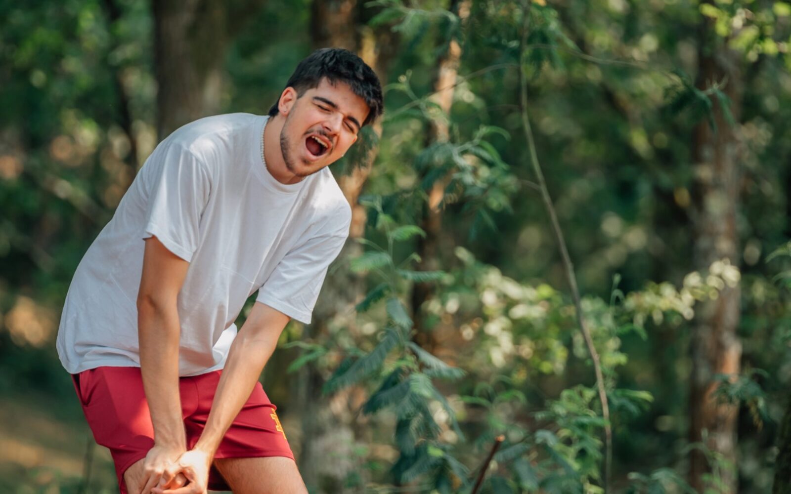 Moški ob nenadni bolečini v kolenu, ki instinktivno reagira – preklinjanje je naravni odziv telesa na bolečino.