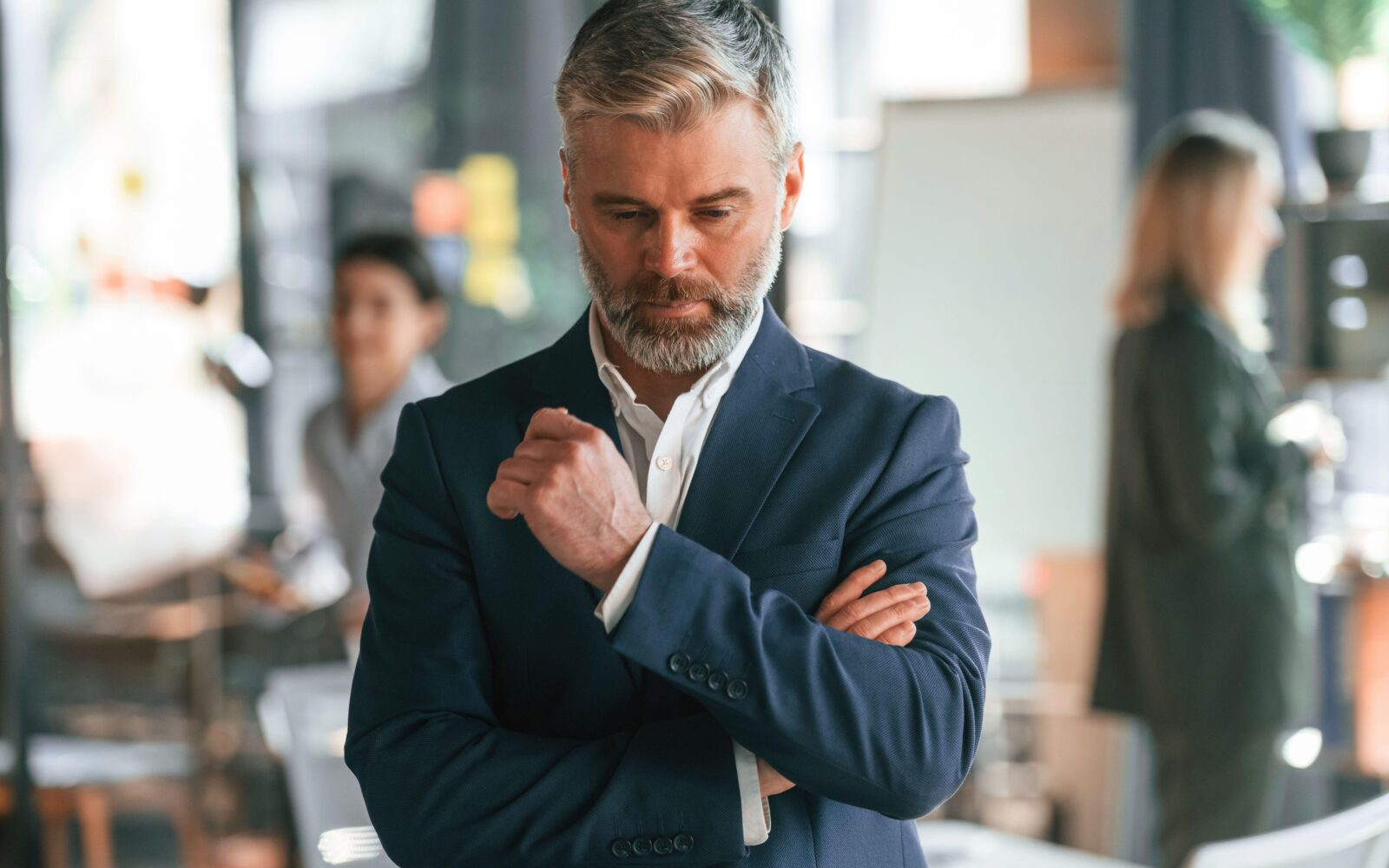 Moški srednjih let v poslovnem okolju, zamišljen in čustveno odtujen, simbol notranje praznine in nevidne travme iz otroštva.