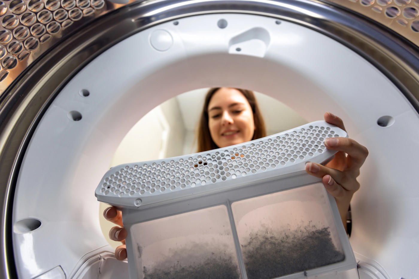 Oseba odstranjuje filter za vlakna iz sušilnega stroja.