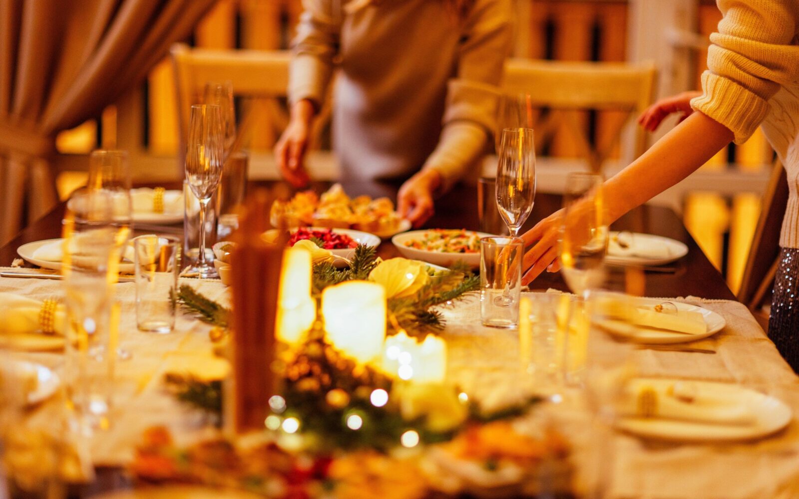 Okrašena praznična miza polna krožnikov, kozarcev, venčkov za dekoracijo