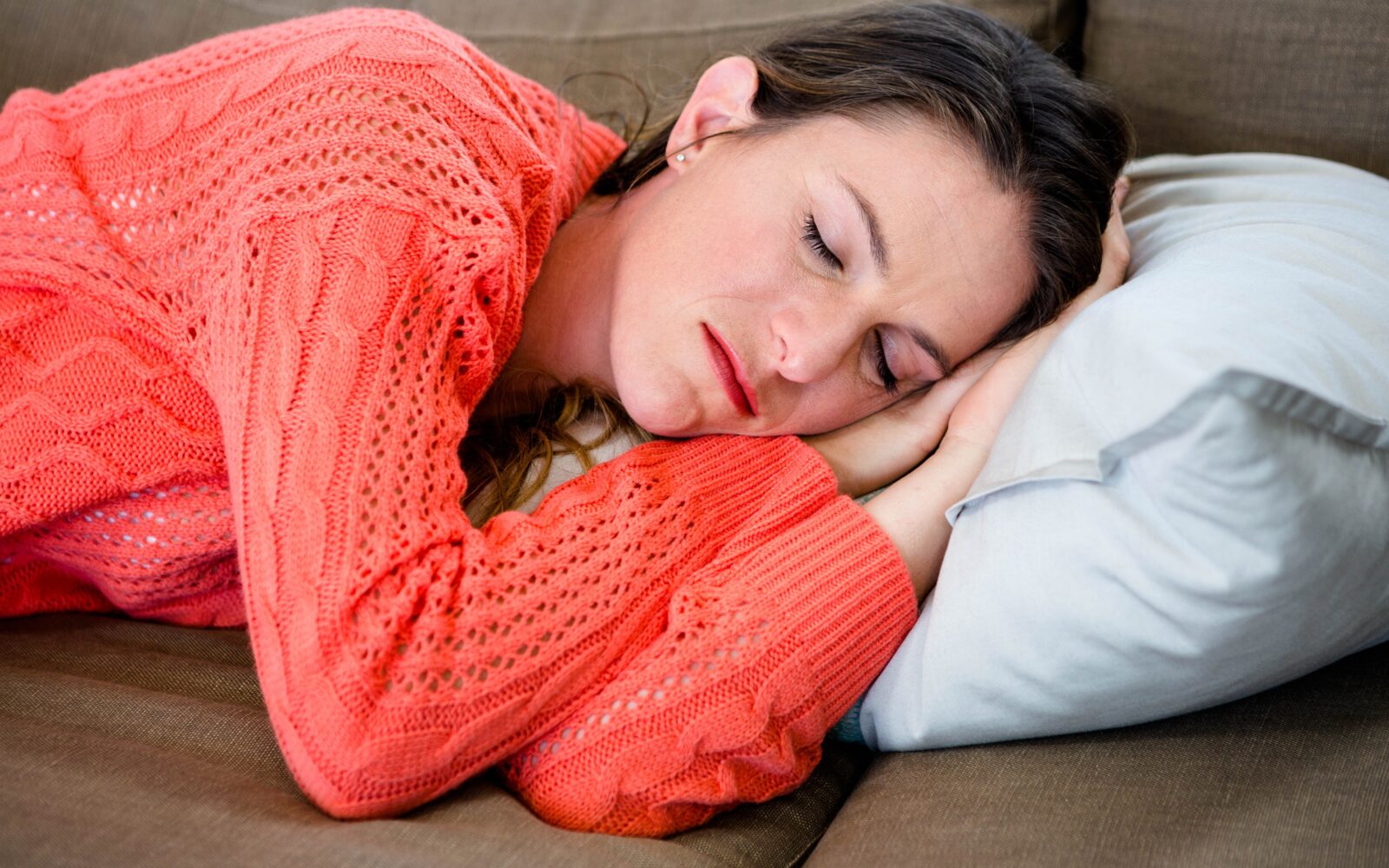 Ženska v oranžnem puloverju je zaspala na kavču, popoldanski počitek, popoldanski dremež