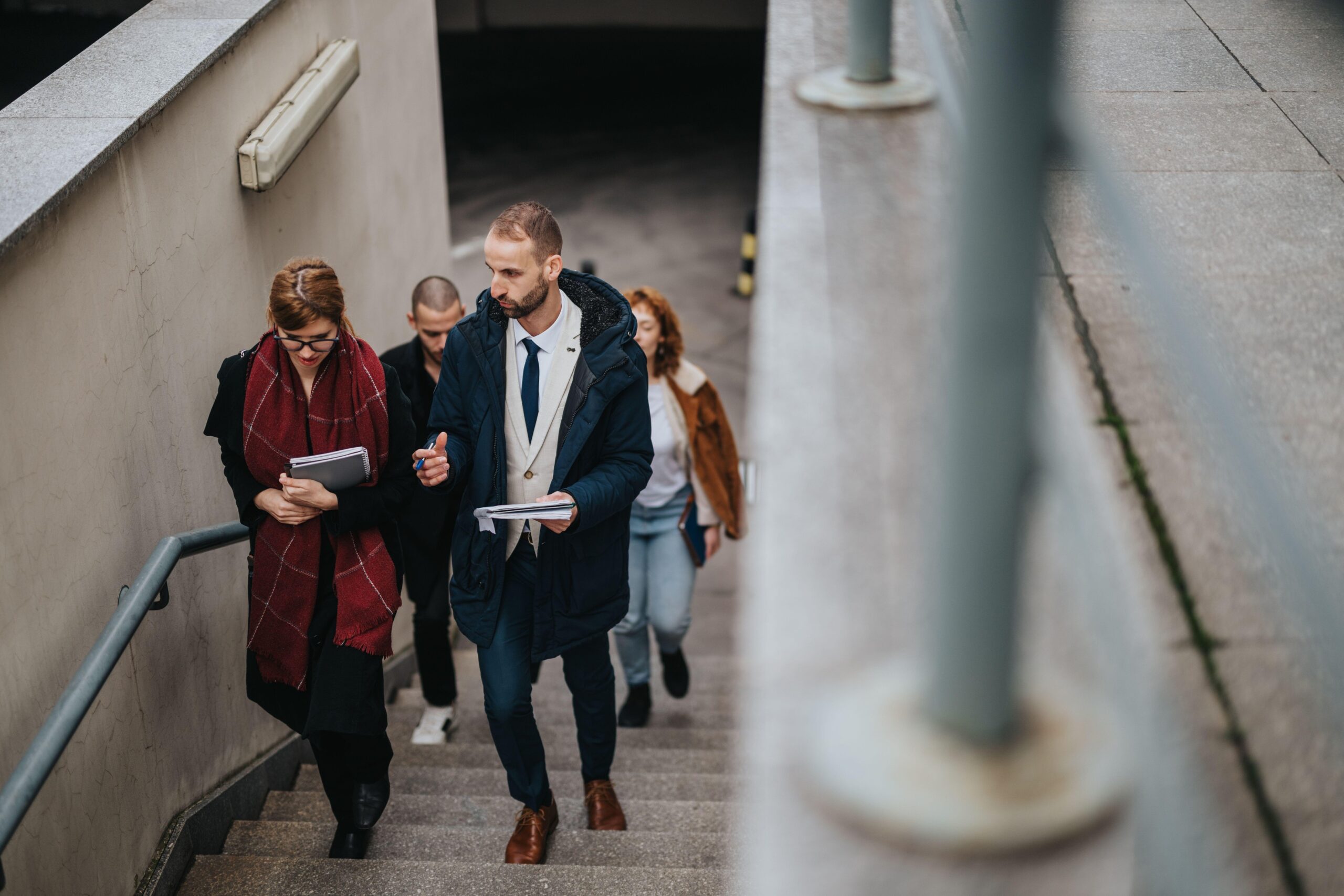 Skupina poslovnežev hodi po stopnicah in se pogovarja, šli so na sprehod po obroku