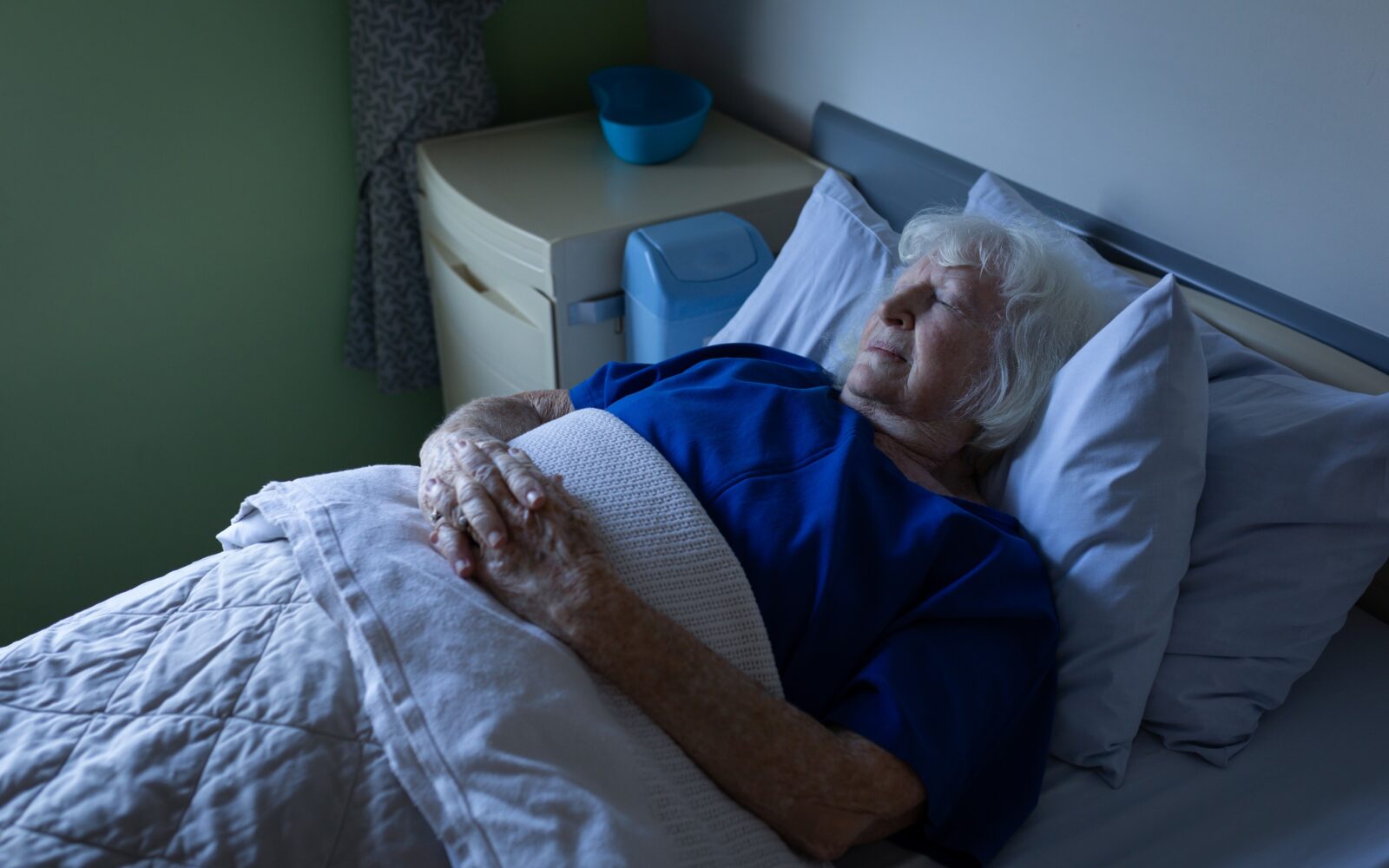 Starejša ženska spi na hrbtu s prekrižanimi rokami na trebuhu