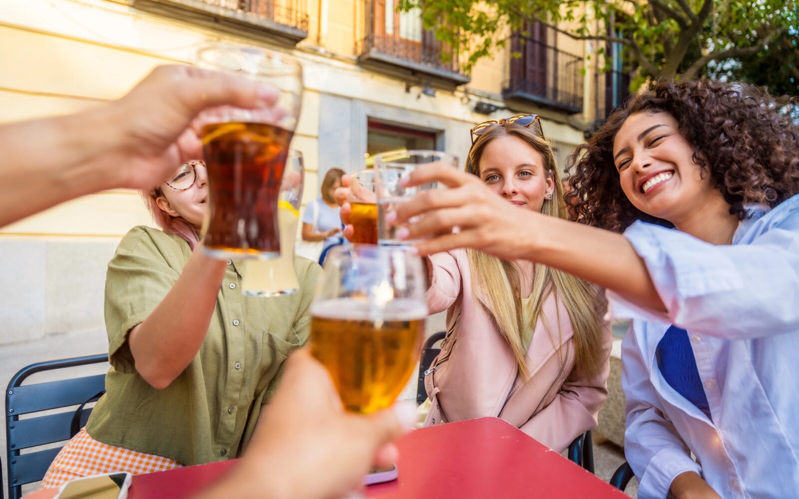 Skupina prijateljev sedi za mizo zunaj in nazdravlja - eni s pivom, drugi z vodo, ostali z gaziranimi pijačami - kaj je najboljša izbira?