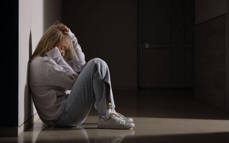 žalostna in depresivna ženska sedi na tleh