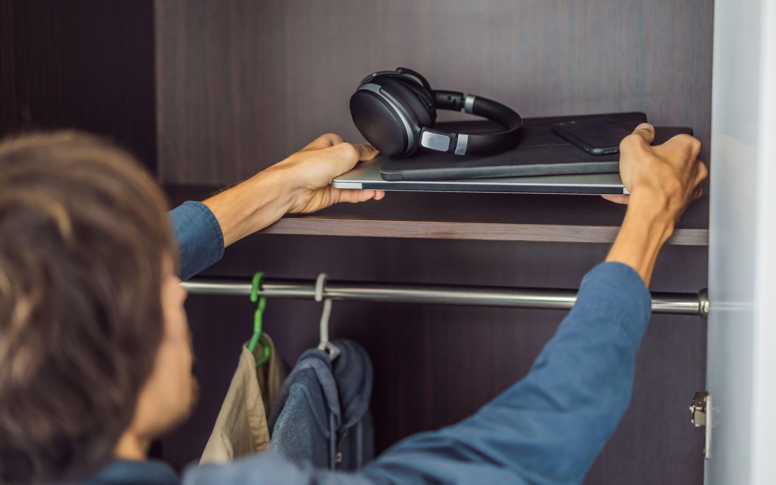 Moški pospravlja elektronske naprave v omaro - digitalni detox