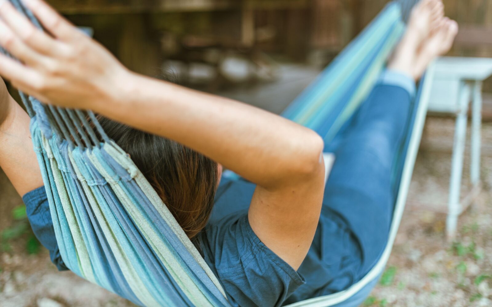Mlada ženska počiva v gugalni vreči na vrtu - pomen počitka za telesno in duševno zdravje