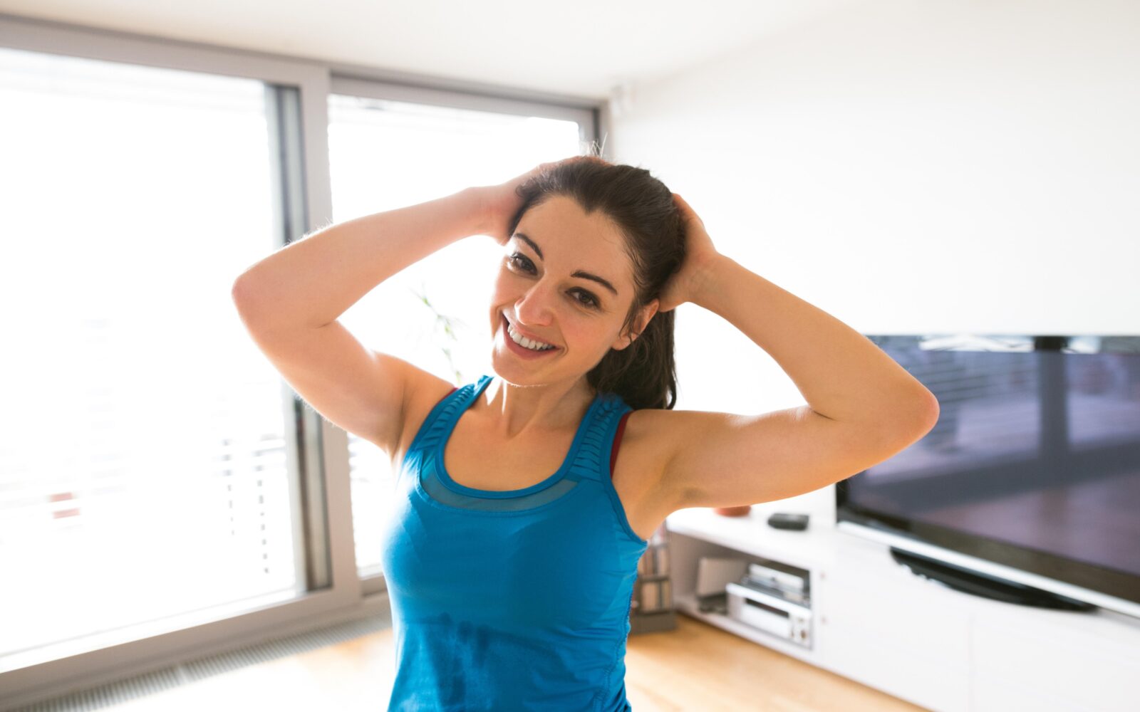 Ženska izvaja vajo za razteg vratu v dnevni sobi doma.