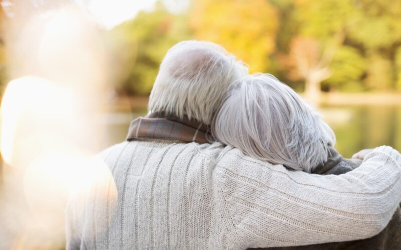 Starejši sivolasi par se objema v jesenskem dnevu