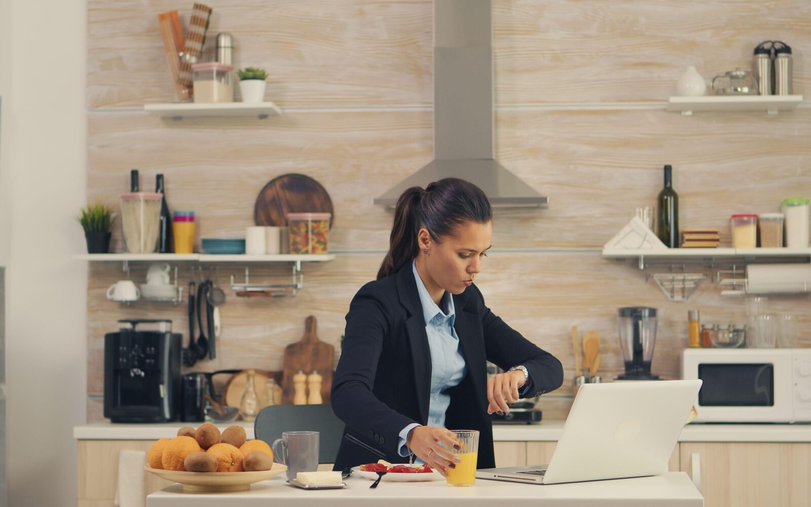 Stresno življenje in hitenje mlade ženske zjutraj - je zajtrk in zraven dela na računalniku