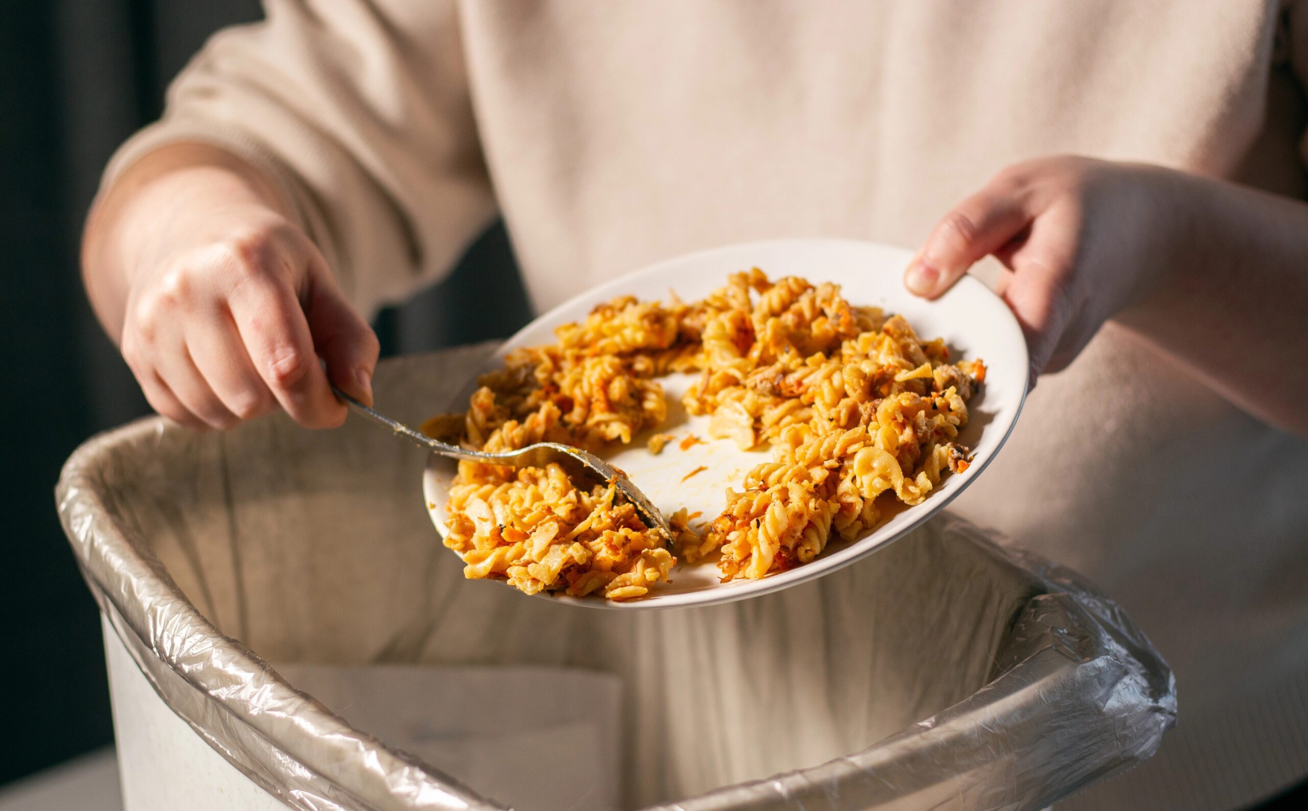 Ženska meče ostanke hrane v koš za smeti