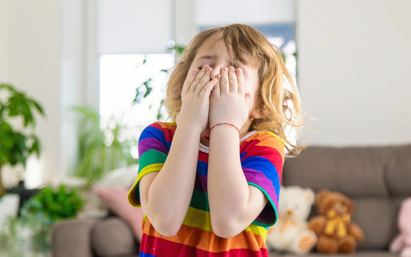 Utrujen, bled, razdražen otrok se zaradi glavobola drži za glavo, kar je lahko znak anemije