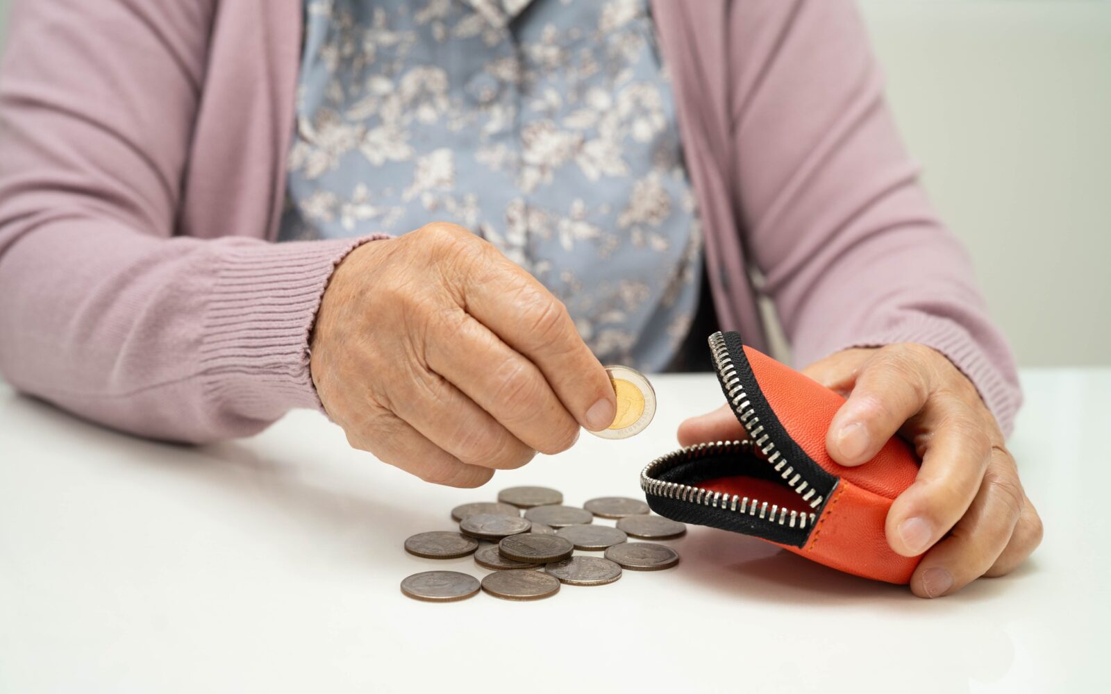 Starejša oseba z denarnico v roki, ki ponazarja demenco, izgubo presoje in tveganja pri ravnanju z denarjem