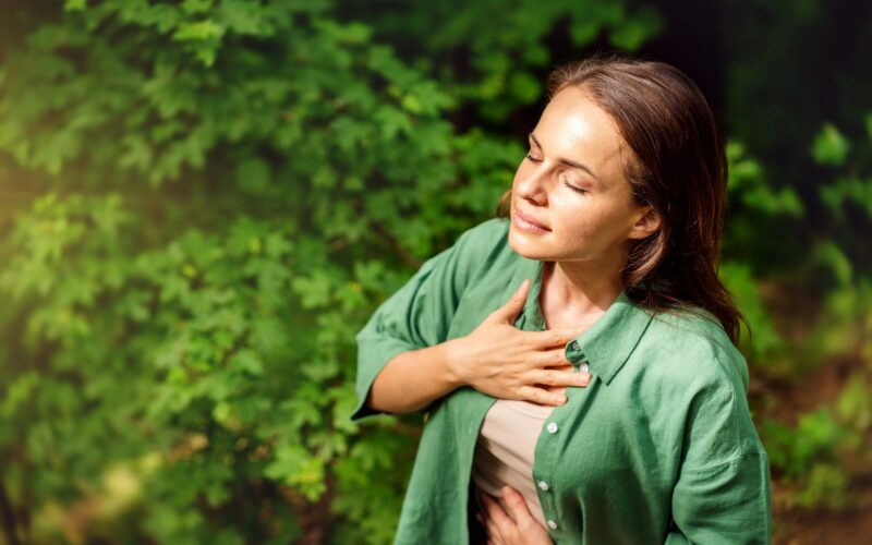 mlada odrasla ženska, ki v gozdu izvaja dihalne vaje