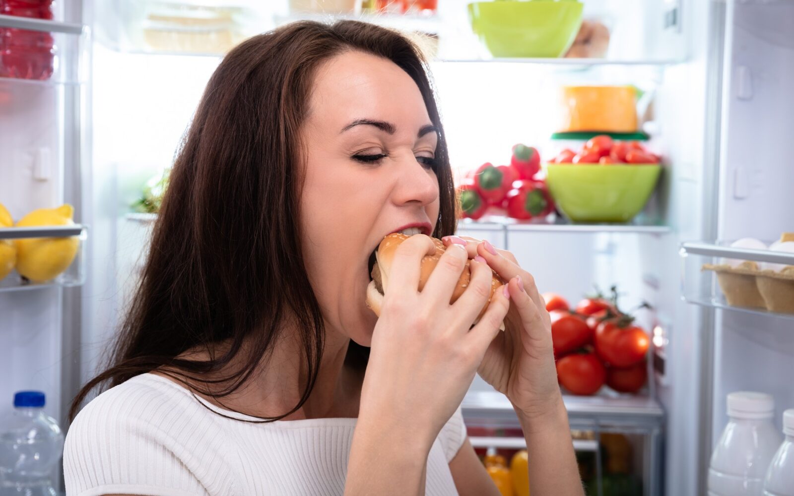 Ženska pred odprtim hladilnikom impulzivno je hamburger