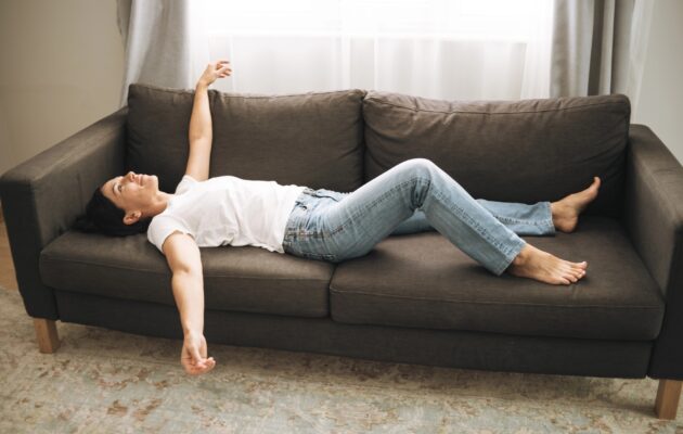 Utrujena ženska leži na kavču