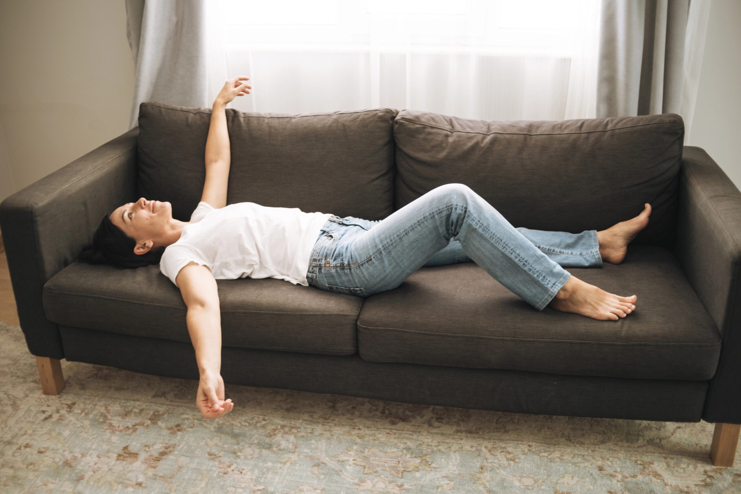 Utrujena ženska leži na kavču