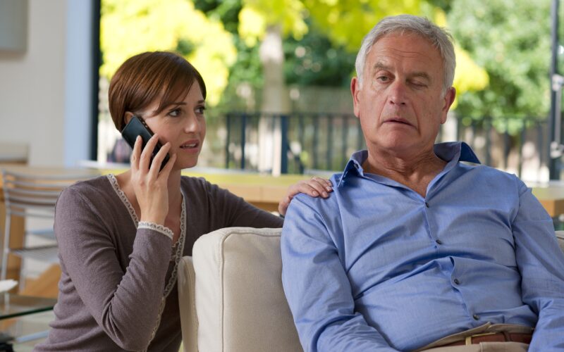 Starejši moški ima možgansko kap. Ima oslabelost obraza. Ženska kliče rešilca.