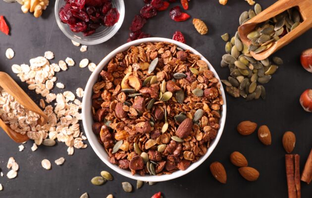 Skleda ovseen kaše z dodatkom oreščkov, mandljev, semen, brusnic, cimeta in orehov za zdrav in uravnotežen zajtrk