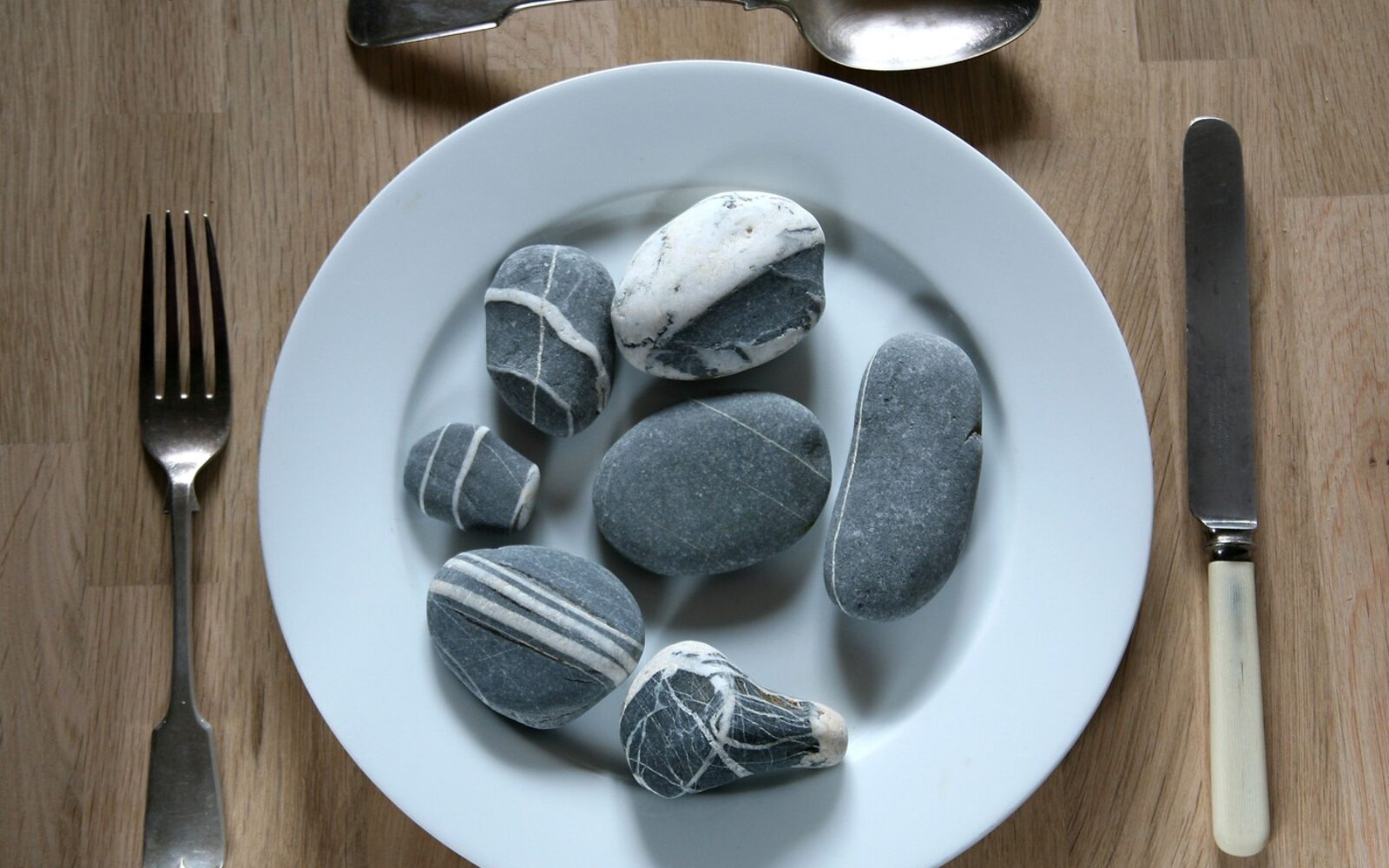 Krožnik s kamni kot simbol motnje pica, pri kateri ljudje uživajo neprehranske snovi