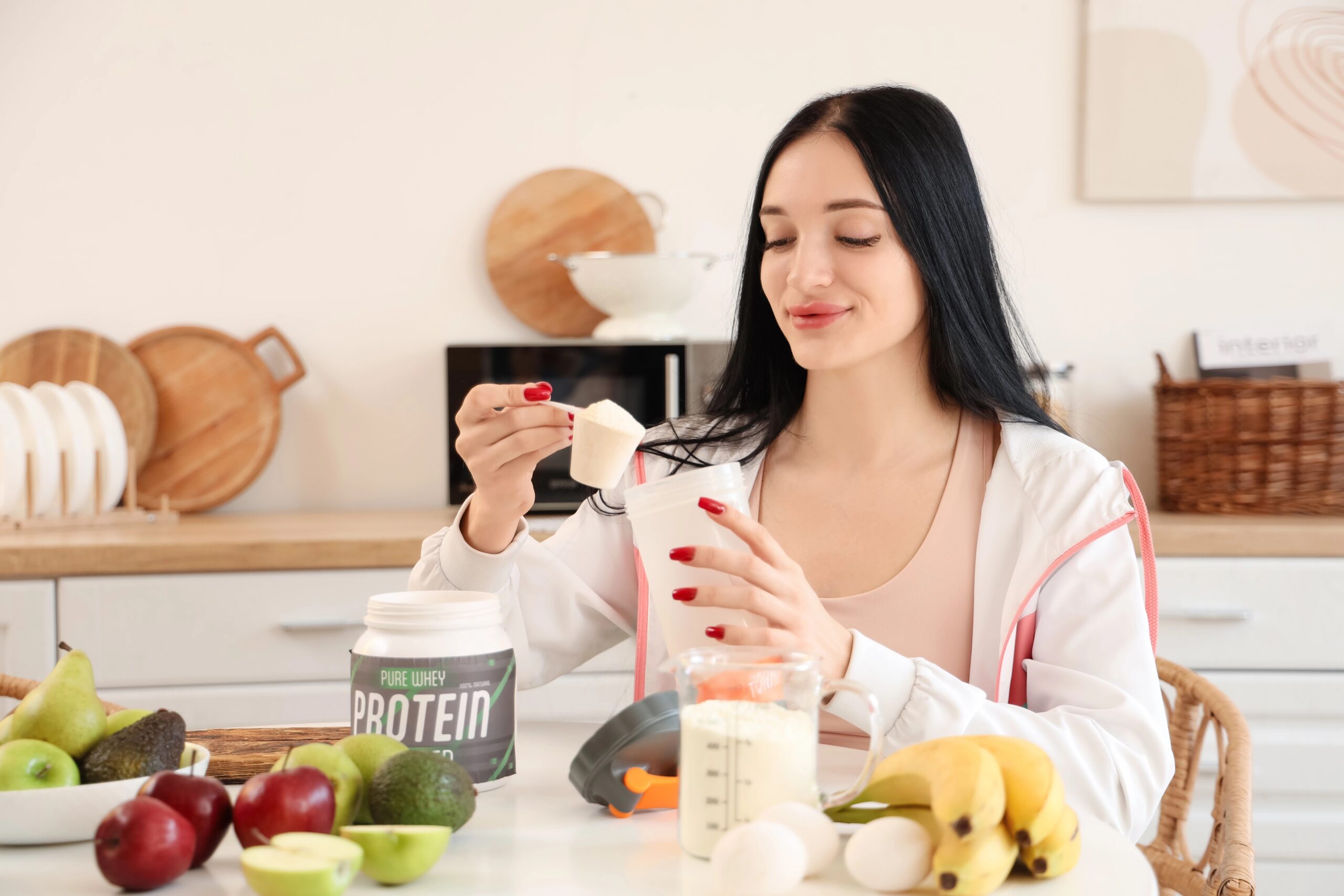 Mlada ženska si za kuhinjsko mizo dela proteinski napitek