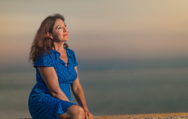 starejša ženska zasanjano gleda sončni zahod - čustvena rast