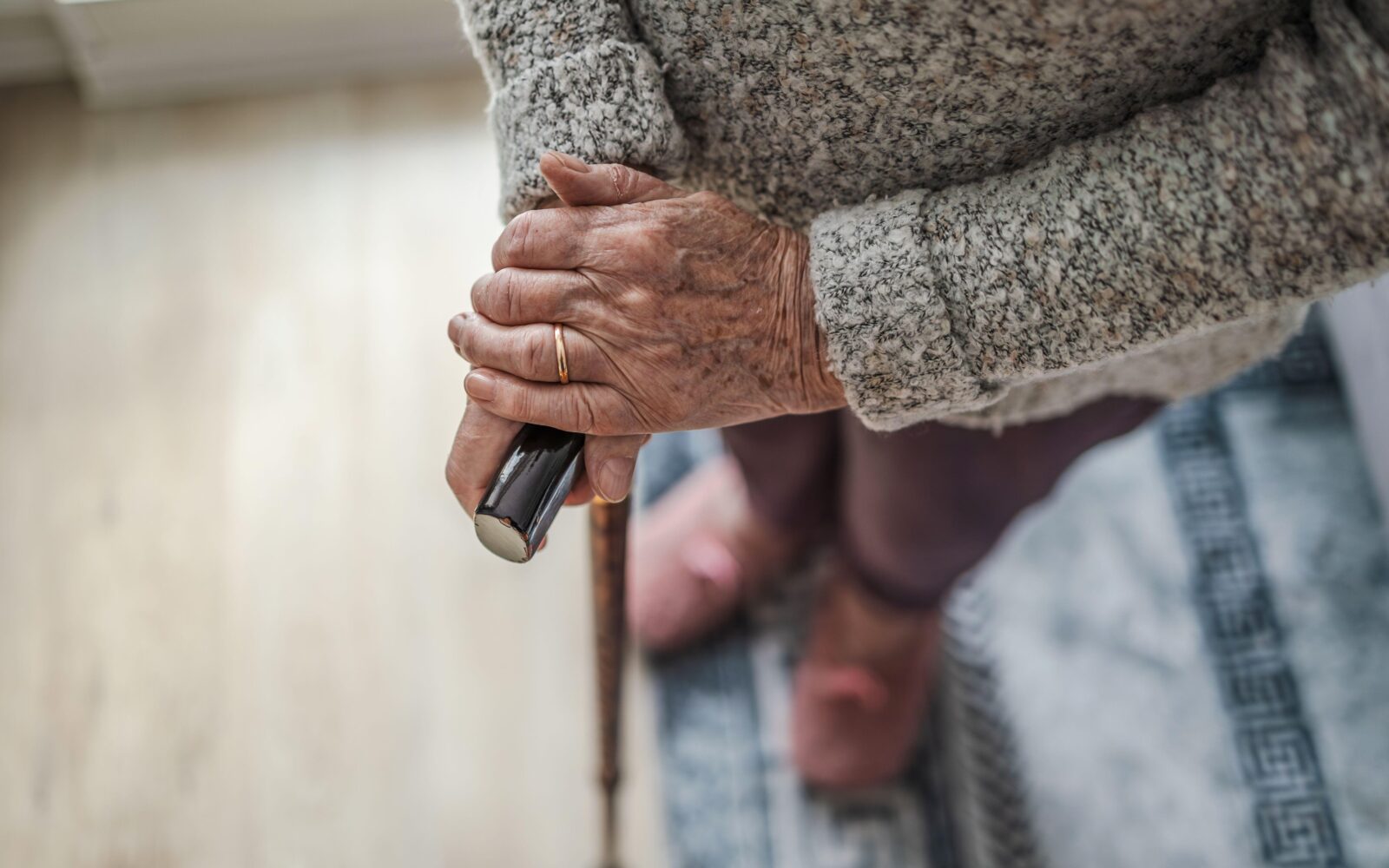 Starejša ženska stoji s sprehajalno palico v rokah