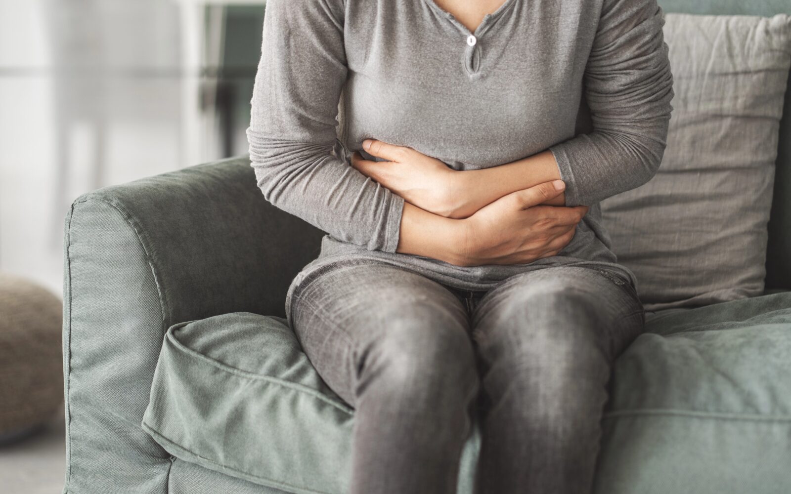 Ženska se drži za trebuh, ker jo boli