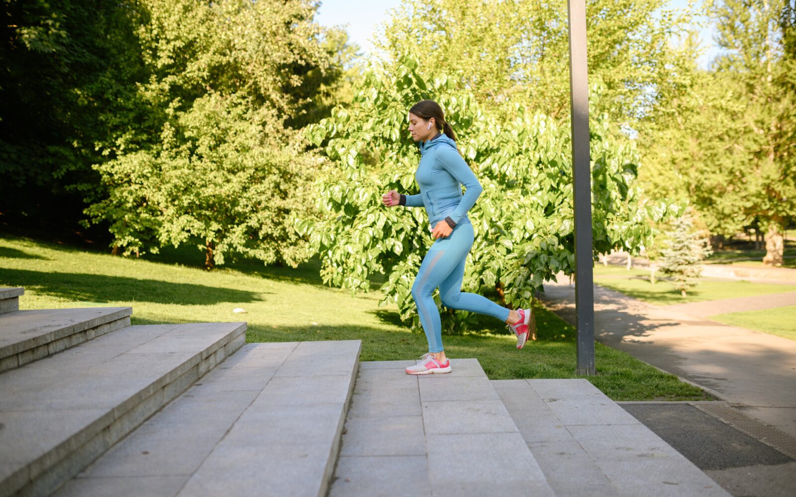 Mlada ženska med jutranjo telovadbo teče po stopnicah v parku