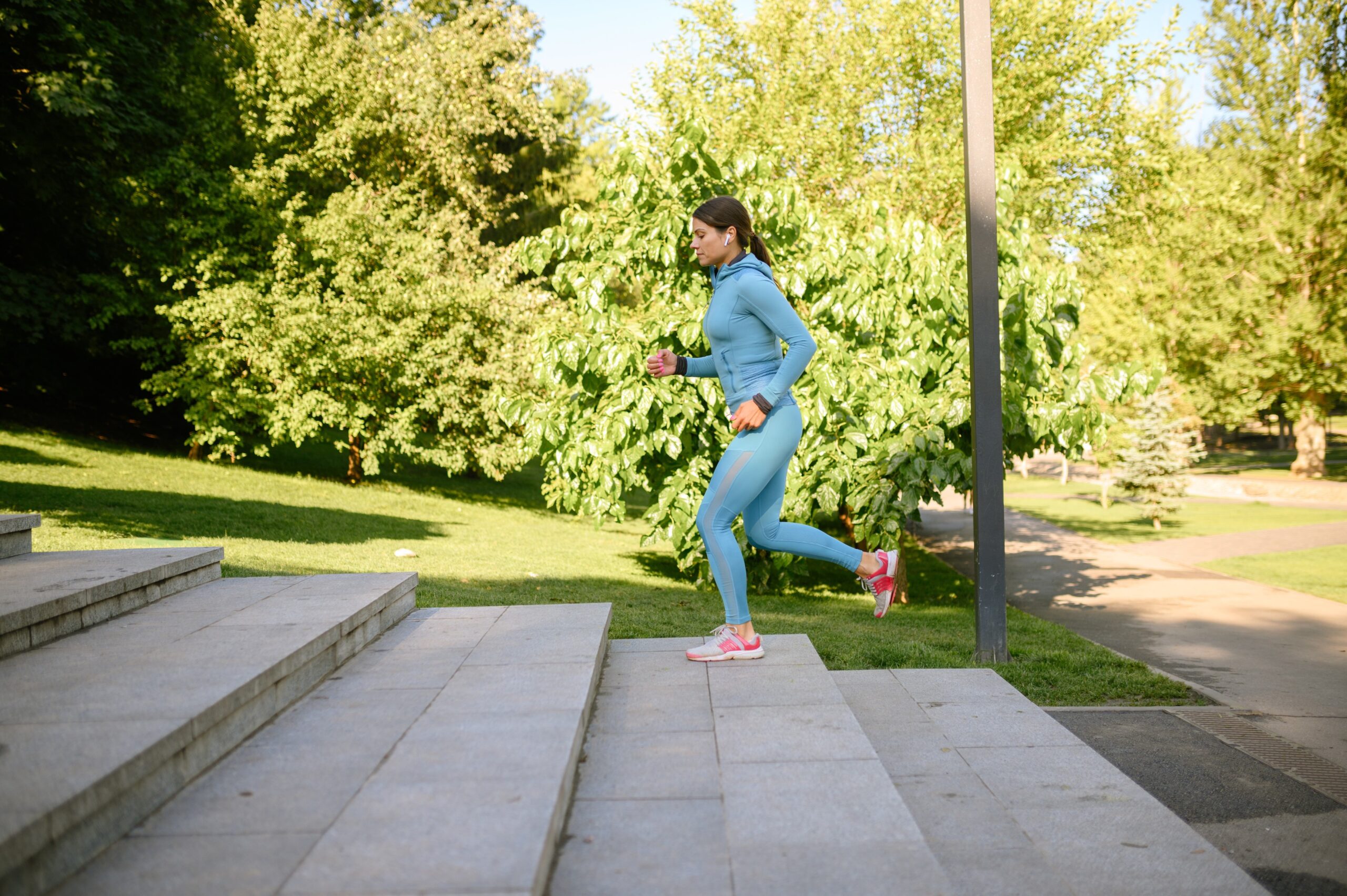 Mlada ženska med jutranjo telovadbo teče po stopnicah v parku