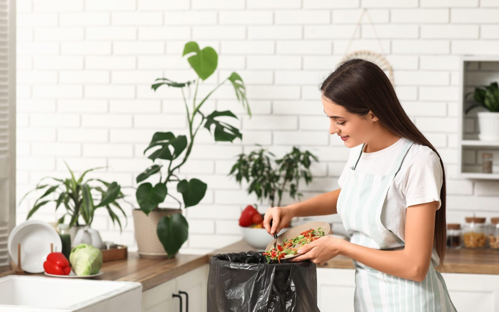 Ženska v koš za smeti meče stran hrano.