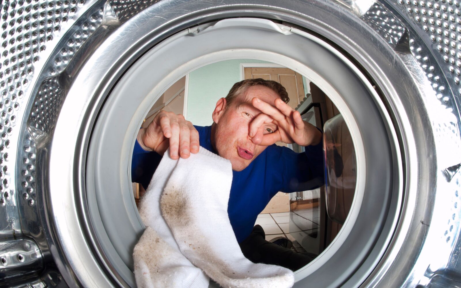 Moški daje nogavice v stroj in se drži za nos od smradu, ki prihaja iz njegovih nogavic.