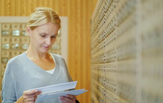 Ženska bere vabilo v nabiralniku za Program Svit za zgodnje odkrivanje raka debelega črevesa