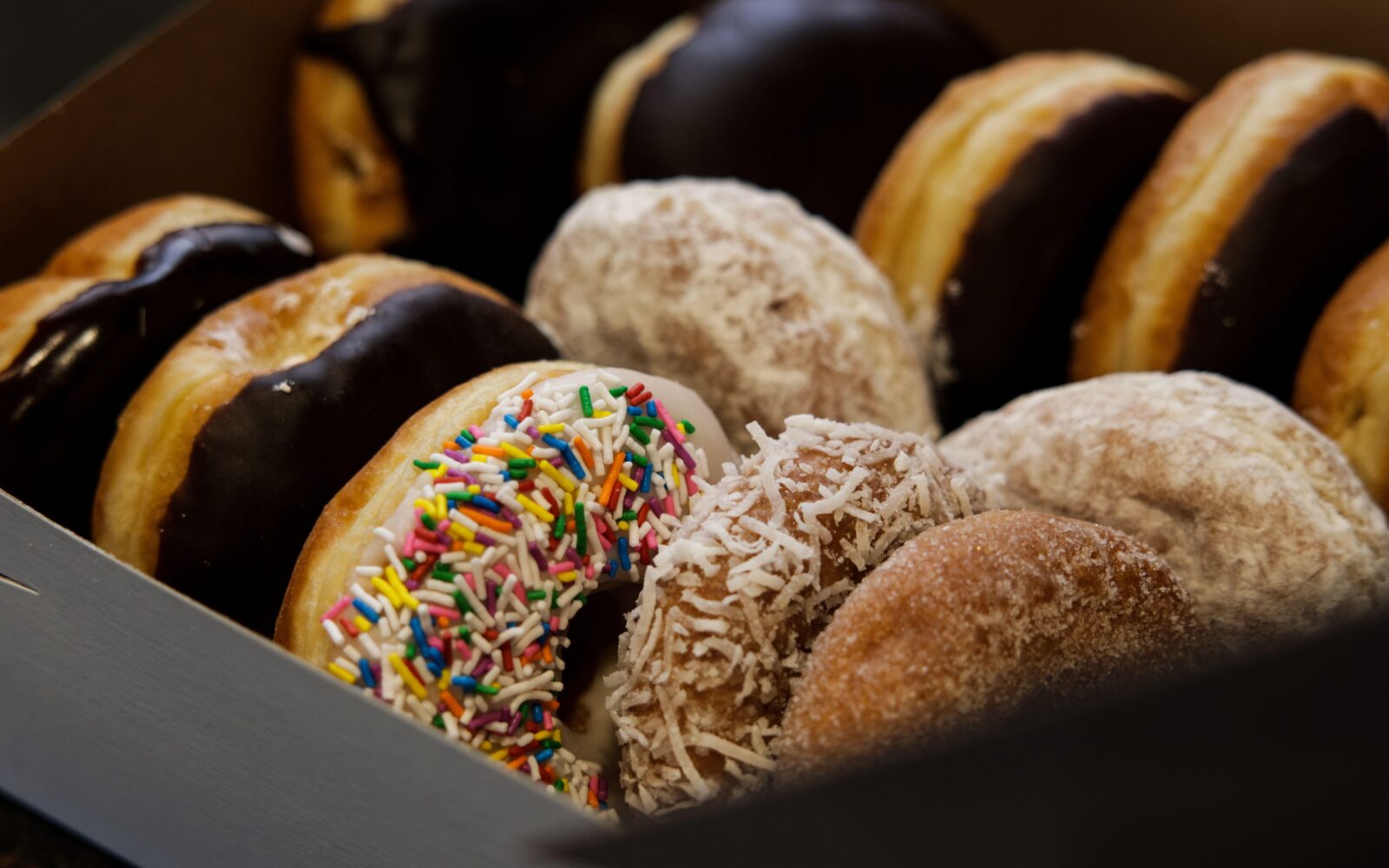 Škatla sveže pečenih sladkih okrašenih krofov