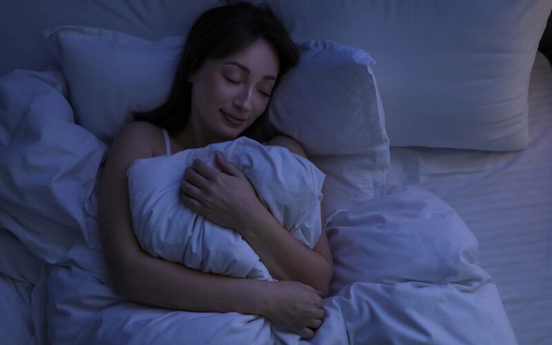 Lepa ženska, ki spi v postelji doma.