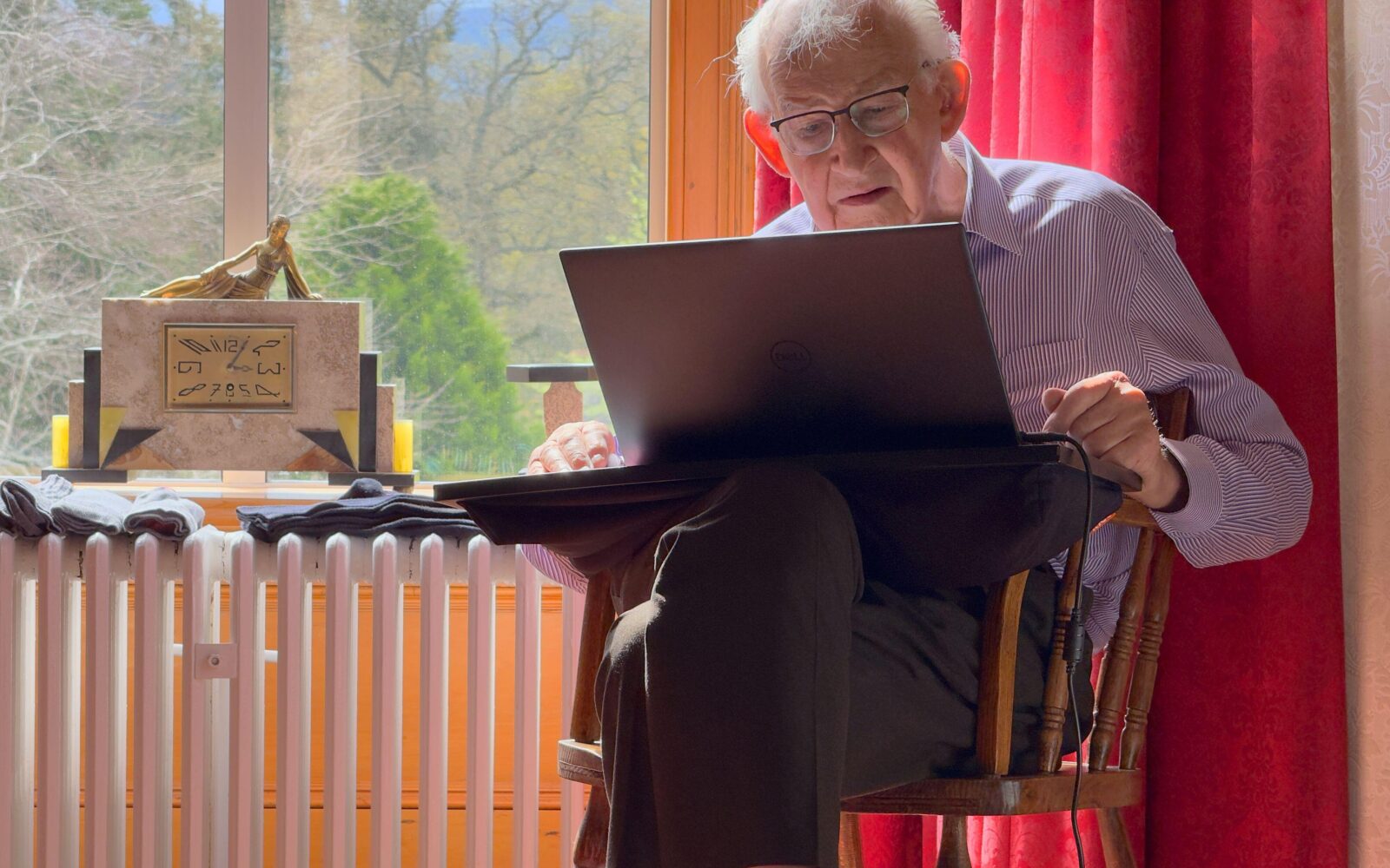 Starejši moški sedi za računalnikom