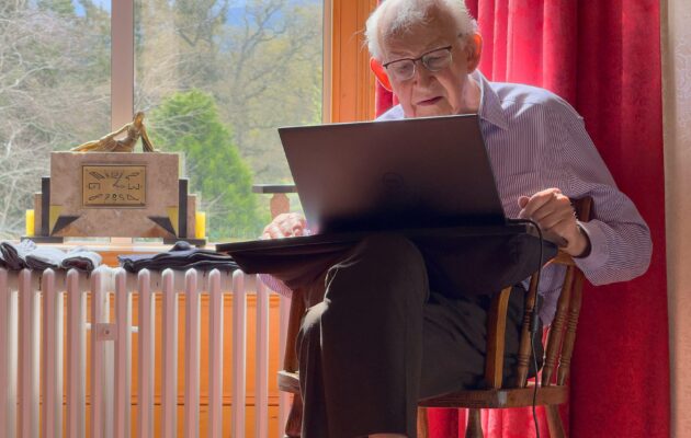 Starejši moški sedi za računalnikom