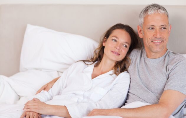Srečen par, oba oblečena v pižamo, se objemata v postelji