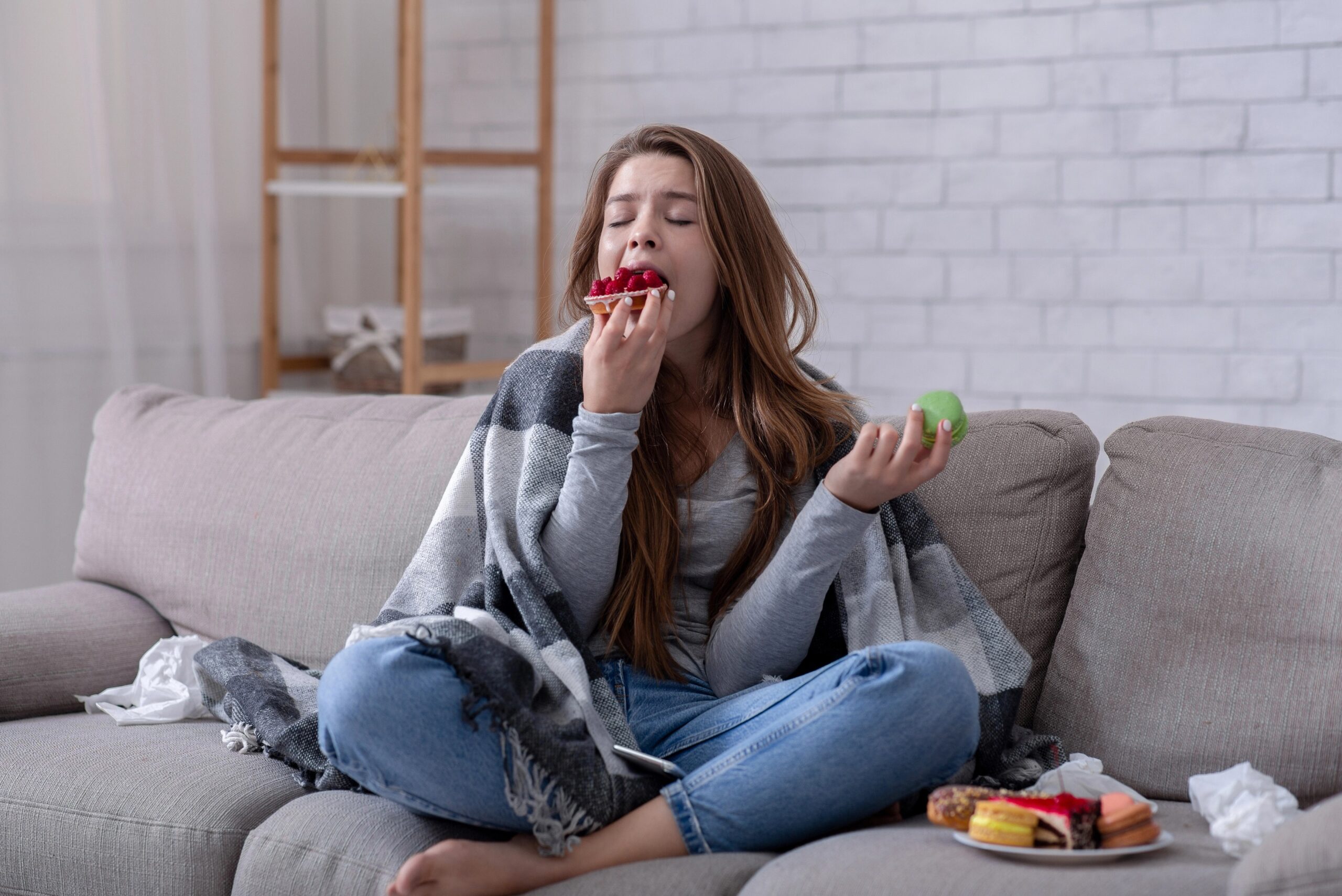 Mlada ženska je utrujena in pod stresom, zato na kavču je hitro in nezdravo hrano