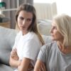 Mama in odrasla hči sedita na kavču in se grdo gledata po prepiru - napeti družinski odnosi lahko vplivajo na staranje naših celic