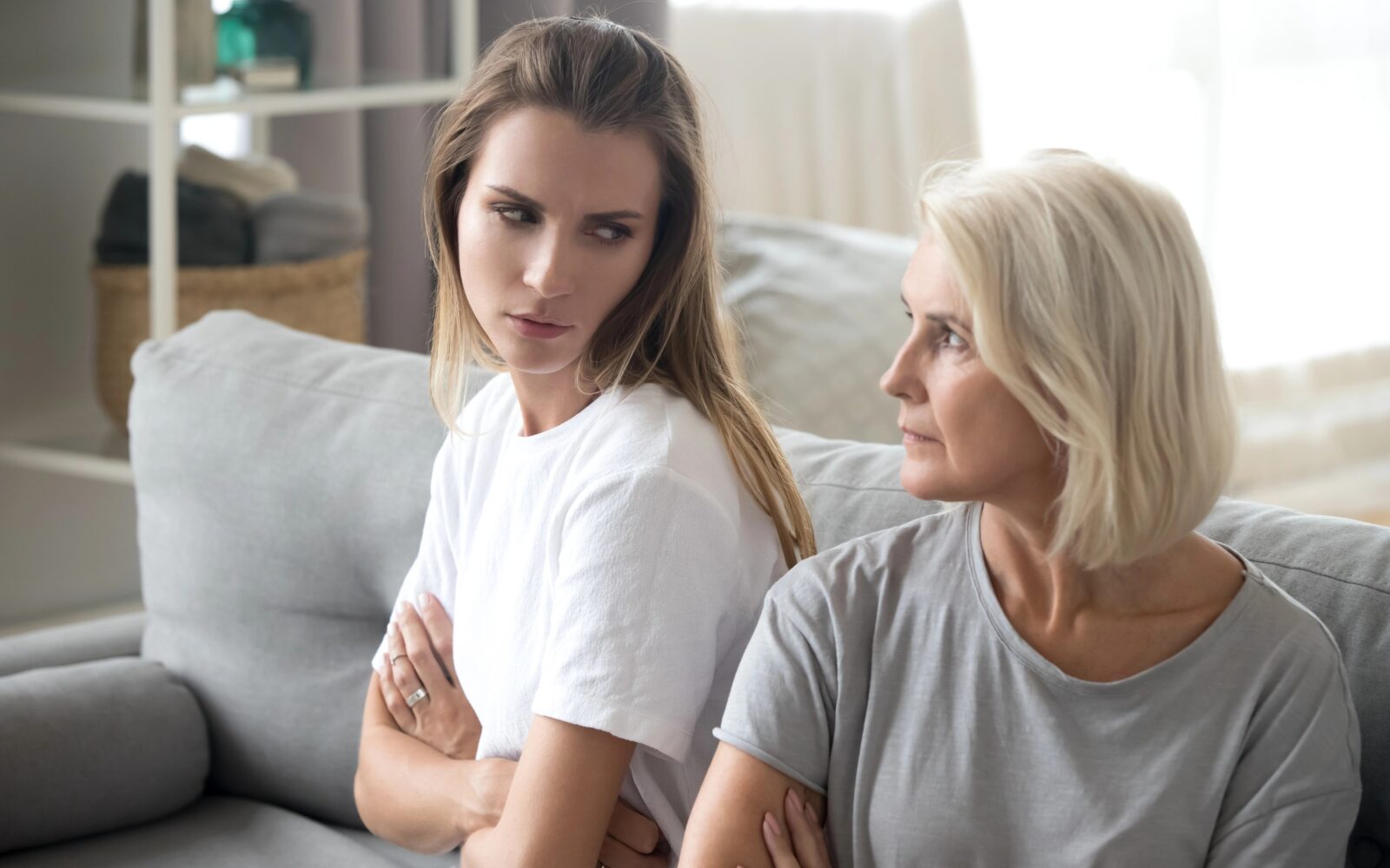 Mama in odrasla hči sedita na kavču in se grdo gledata po prepiru - napeti družinski odnosi lahko vplivajo na staranje naših celic