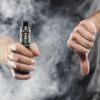 Moški v eni roki drži elektronsko cigareto (e-cigareto, vejp), z drugo pa simbolično kaže, da to odklonilen znak - prst obrnjen navzdol