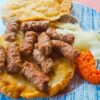 Porcija čevapčičev na somunju z ajvarjem in čebulo na krožniku