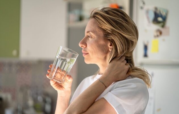 ženska pije kozarec vode zjutraj v kuhinji naravna svetloba
