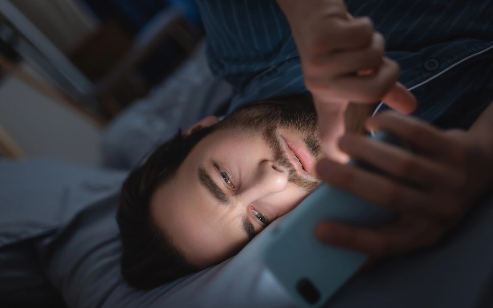 moški s telefonom v postelji igra na spletnih stavah.