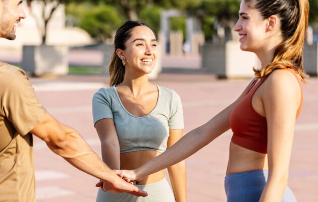 Skupina treh prijateljev si pred vadbo daje roko za motivacijo